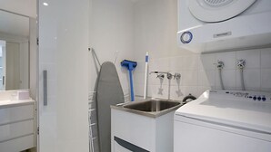 Ett modernt badrum med en inbyggd tvättmaskin, ett handfat och en duschhörna.