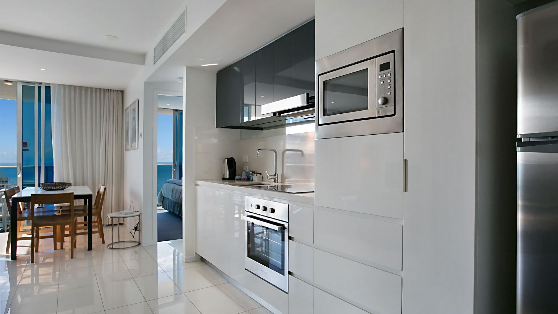 A modern kitchen with white cabinetry, stainless steel appliances, and a dining area with a view.
