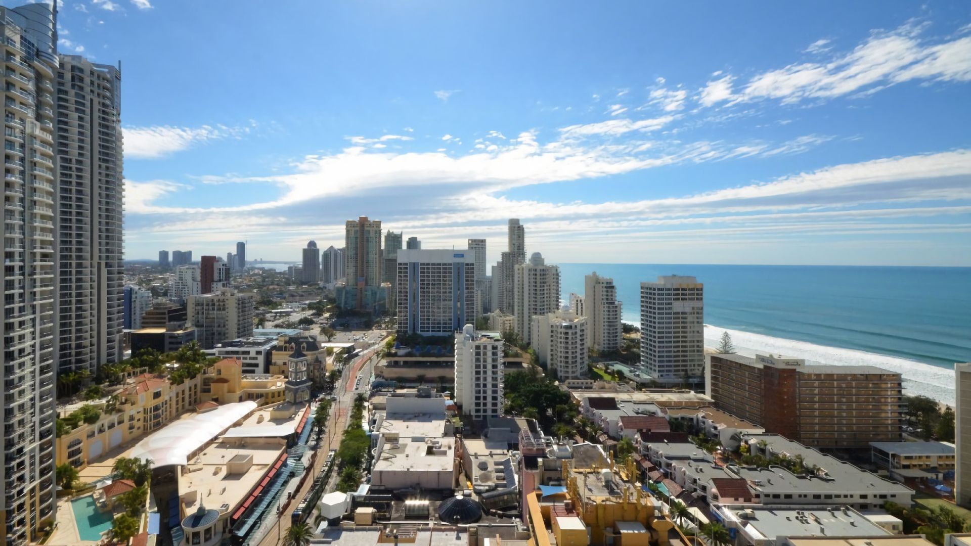 A coastal cityscape with high-rise buildings, a beach, and a clear sky.