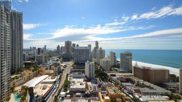 A coastal cityscape with high-rise buildings, a beach, and a clear sky.