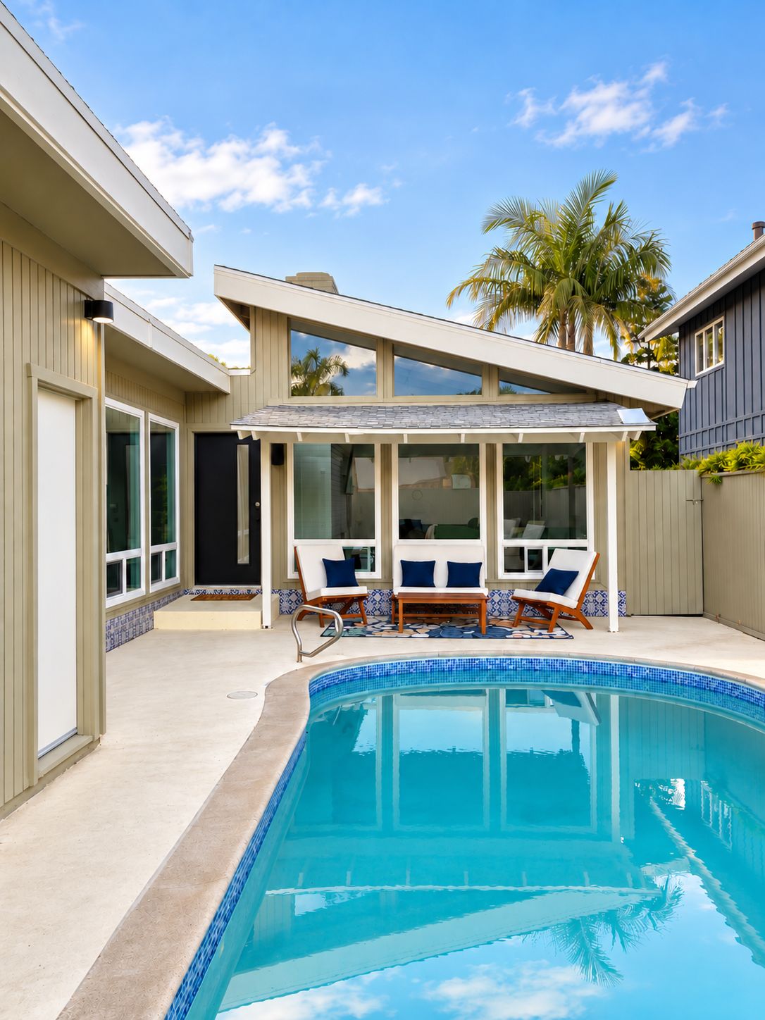 A modern pool area with a covered seating area and two lounge chairs.