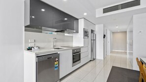 A modern kitchen with stainless steel appliances, a dishwasher, and a microwave. - Orchid Residences Apartment 12105 (Surfers Paradise)