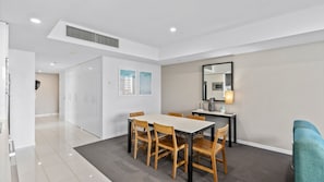 A modern hotel room with a dining area, a sofa, and a large mirror. - Orchid Residences Apartment 12105 (Surfers Paradise)
