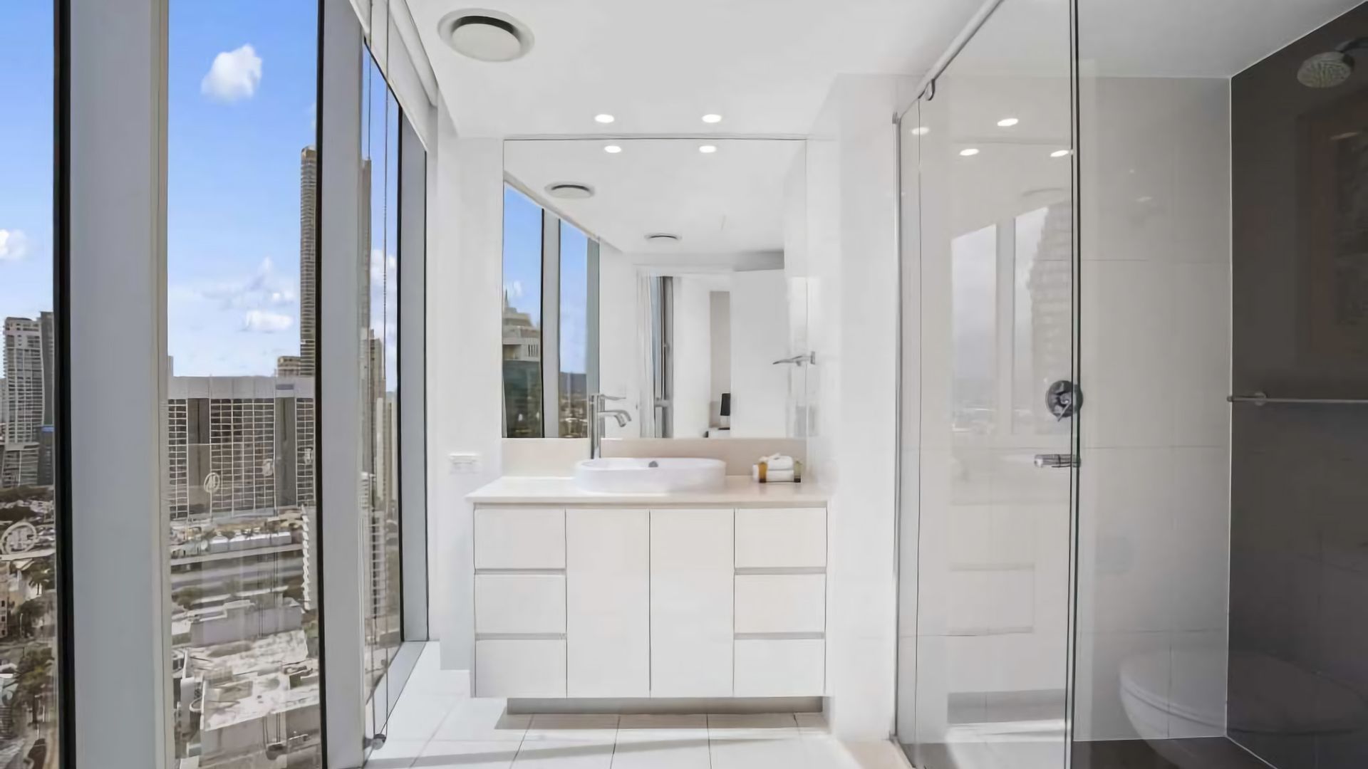 Un bagno moderno con una grande finestra, un lavandino e una doccia.