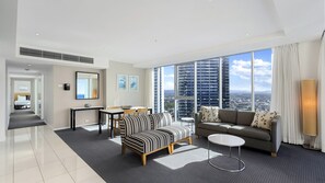 Ein modernes Wohnzimmer mit Sofa, Sessel, Esstisch und Blick auf die Stadt durch große Fenster.