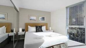 Ein Hotelzimmer mit Bett, Nachttischen, einem Spiegel, Kunstwerken und einem großen Fenster.