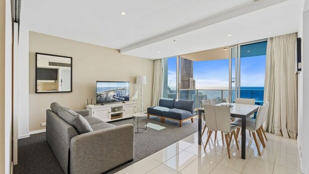 Een moderne hotelkamer met balkon, flatscreen-tv, bank, eettafel en stadszicht.