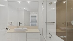 Een moderne badkamer met een grote spiegel, een wastafel en een douche.
