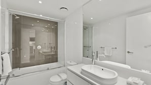 Ett modernt badrum med en duschavdelning med glasväggar, ett fristående badkar, en tvättställsmöbel med en stor tvättställ och en toalett.