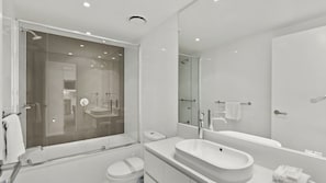 A modern bathroom with a glass-enclosed shower, a freestanding bathtub, a vanity with a large sink, and a toilet. - Orchid Residences Apartment 21705 (Surfers Paradise)