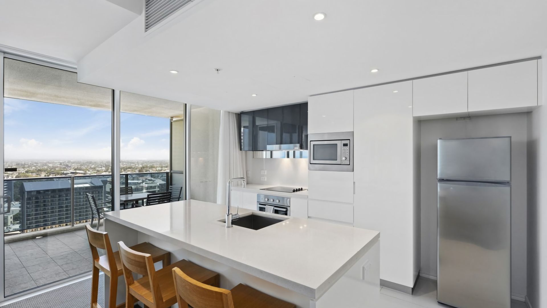 A modern kitchen with a large island, stainless steel appliances, and a city view.