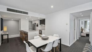 A modern hotel room with a dining area, kitchenette, and a view of the city. - Orchid Residences Apartment 21803 (Surfers Paradise)