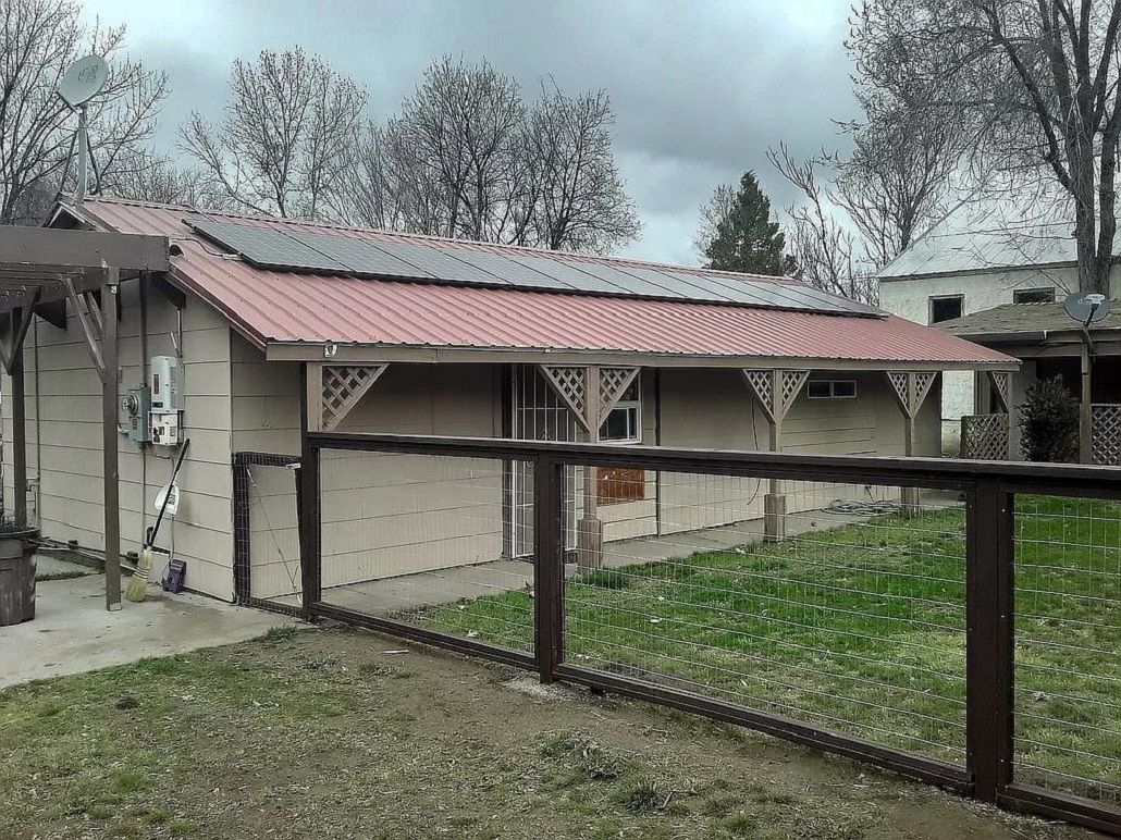 A building with a red roof, a fenced yard, and a satellite dish.