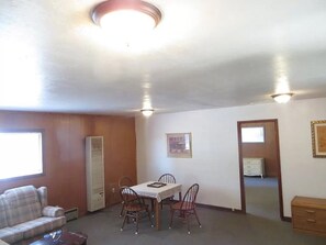 Una habitación con mesa de comedor, sillas, sofá, calefactor y un mueble pequeño.