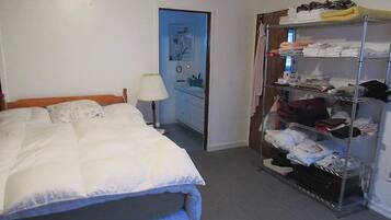 A hotel room with a bed, a wardrobe, and a door leading to a bathroom.
