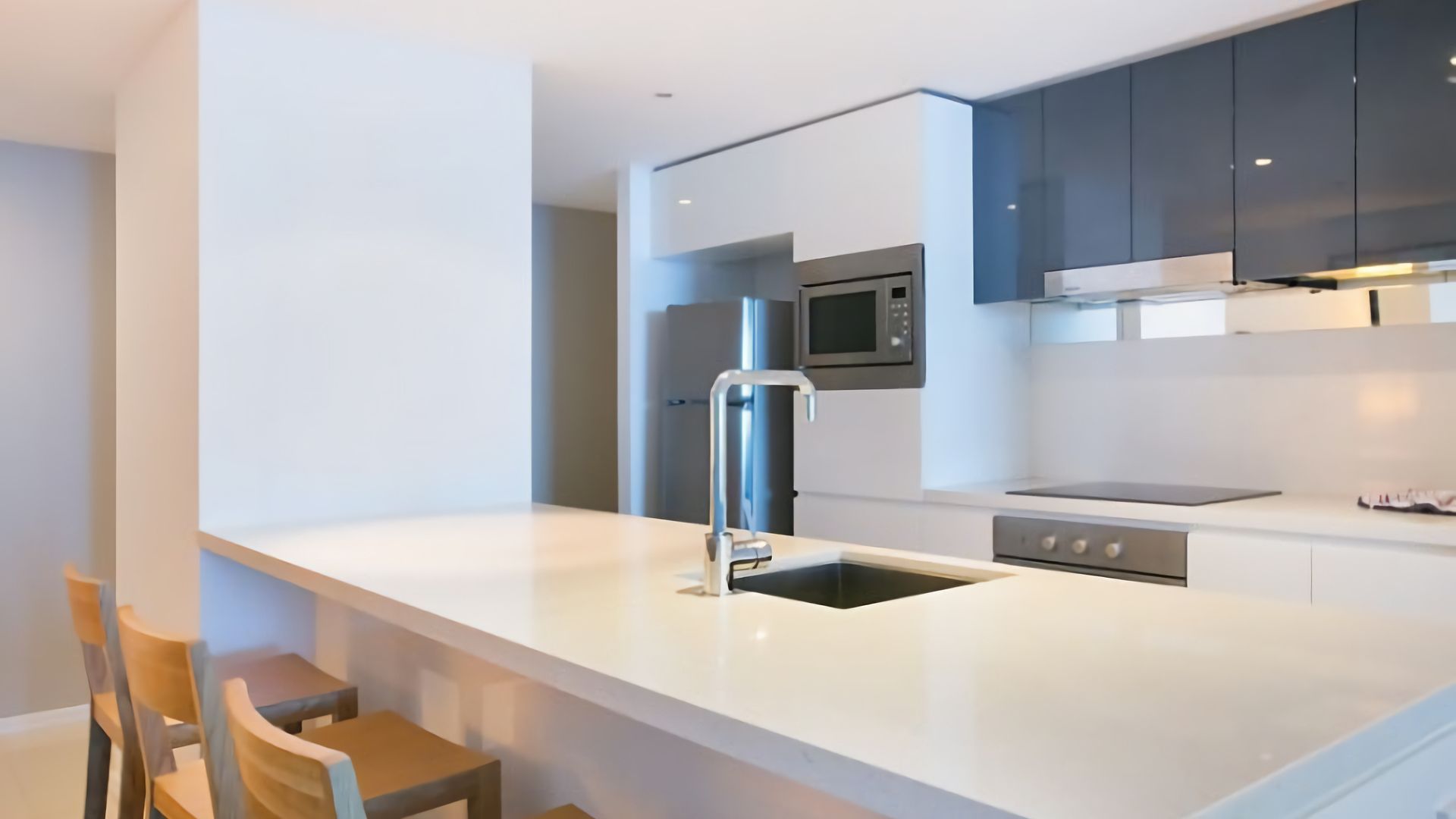 Una cocina moderna con una isla central, electrodomésticos de acero inoxidable y sillas de madera.
