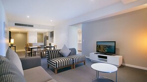 A modern living room with a sofa, a television, and a dining area. - Orchid Residences Apartment 22303 (Surfers Paradise)