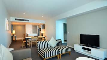 Una sala de estar moderna con un sofá, una televisión y un comedor con sillas y una mesa.