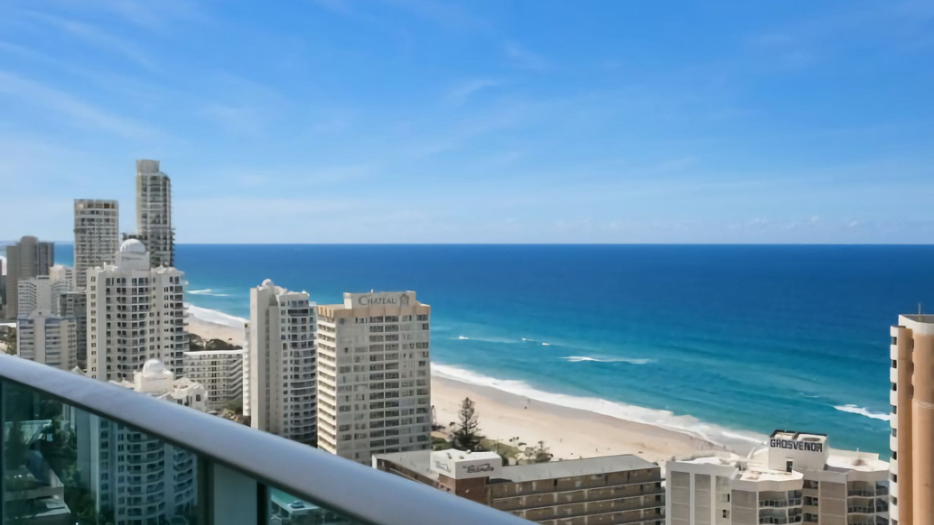 A coastal cityscape with high-rise buildings, a beach, and a clear blue sky.