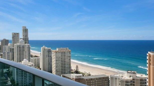 A coastal cityscape with high-rise buildings, a beach, and a clear blue sky. - Orchid Residences Apartment 22303 (Surfers Paradise)