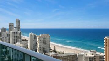 A coastal cityscape with high-rise buildings, a beach, and a clear blue sky.