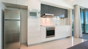 A modern kitchen with a built-in oven, microwave, and stainless steel refrigerator. - Orchid Residences Apartment 22306 (Surfers Paradise)