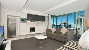 A modern living room with a grey sofa, a coffee table, and a TV. - Orchid Residences Apartment 22306 (Surfers Paradise)
