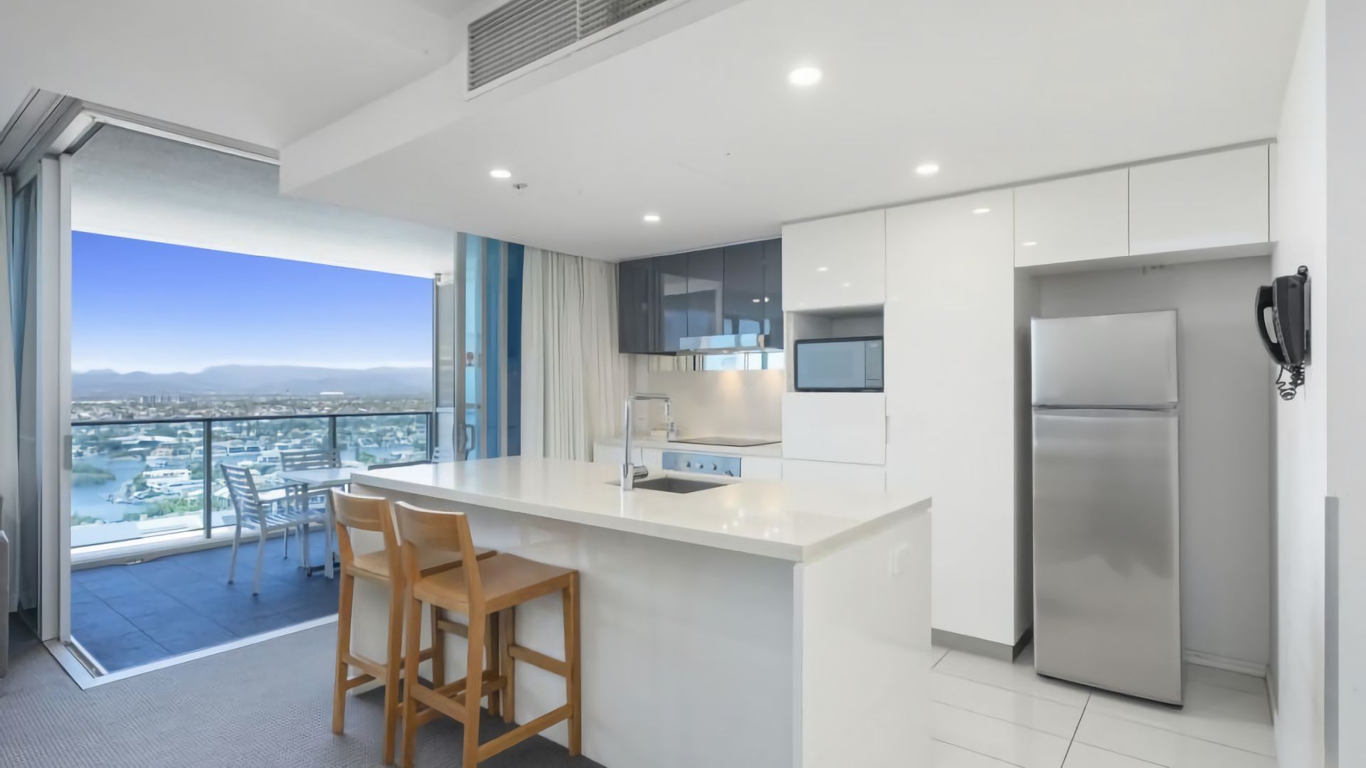 A modern kitchen with a large island, stainless steel appliances, and a view of the city.