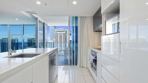 A modern kitchen with a large window, a built-in oven, and a view of a city skyline. - Orchid Residences Apartment 22405 (Surfers Paradise)