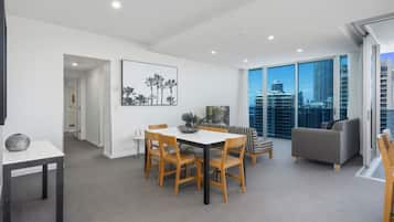 A modern dining area with a table and chairs, a sofa, and a large window with a city view.