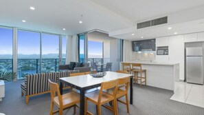 A modern apartment with a dining area, kitchen, and a balcony with a city view. - Orchid Residences Apartment 22405 (Surfers Paradise)