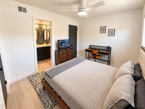 A bedroom with a bed, a desk, a chair, a television, and a ceiling fan. - Modern 2BR | Near Downtown Austin & SoCo (Austin)