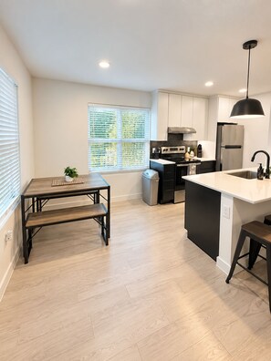 A modern kitchen with a central island, built-in appliances, and a dining area with a bench. - Modern 2BR | Near Downtown Austin & SoCo (Austin)