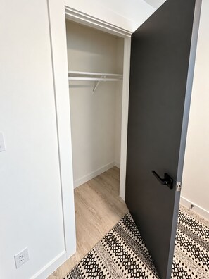 A room with a walk-in closet, a patterned rug, and a door with a black handle. - Modern 2BR | Near Downtown Austin & SoCo (Austin)