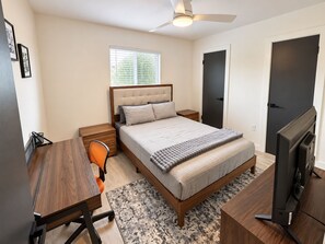 A bedroom with a bed, bedside table, chair, desk, TV, and a ceiling fan. - Modern 2BR | Near Downtown Austin & SoCo (Austin)