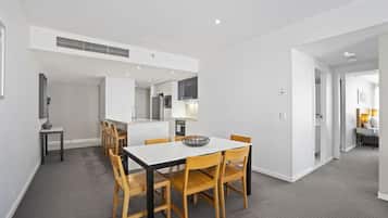 A modern kitchen with white cabinets, a central island, and a dining area with a white table and wooden chairs.