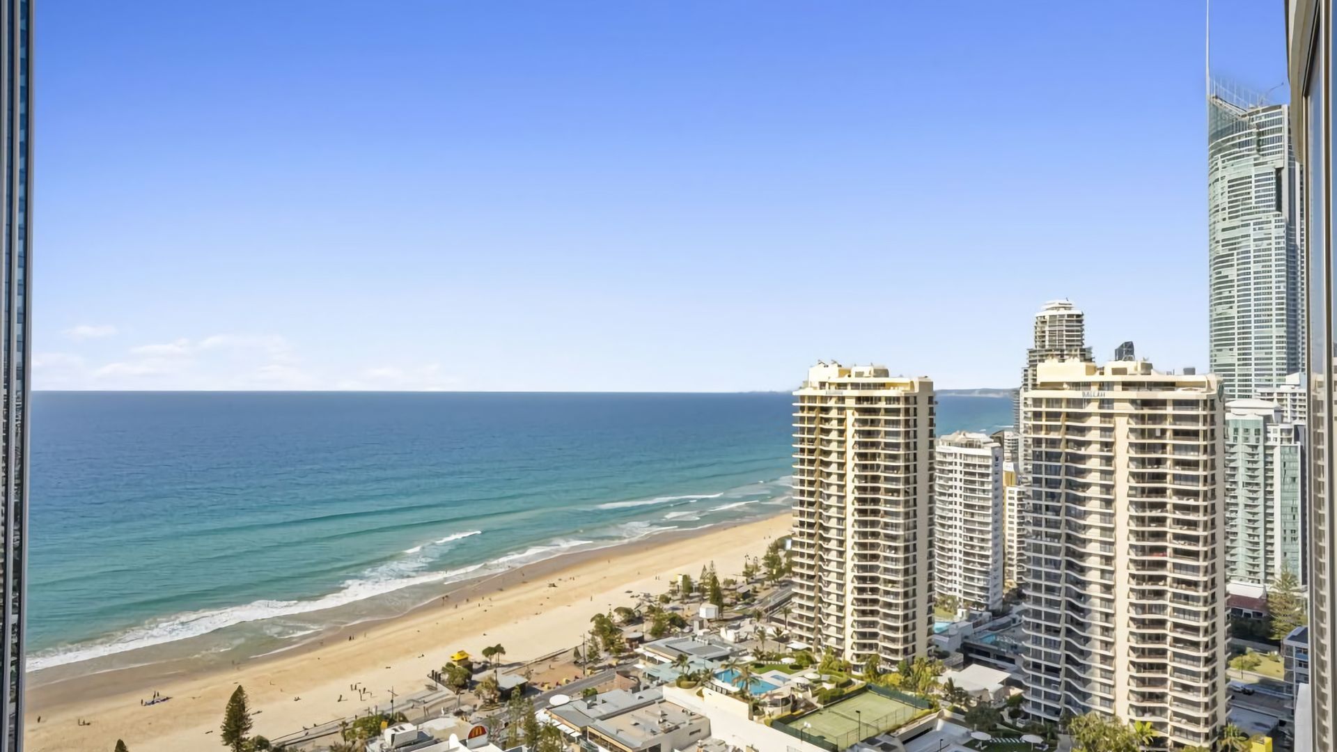 A beachfront hotel with multiple high-rise buildings, a sandy beach, and the ocean.