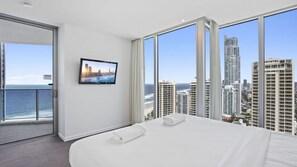 A hotel room with a large bed, a television, and a balcony with a city view. - Orchid Residences Apartment 22604 (Surfers Paradise)