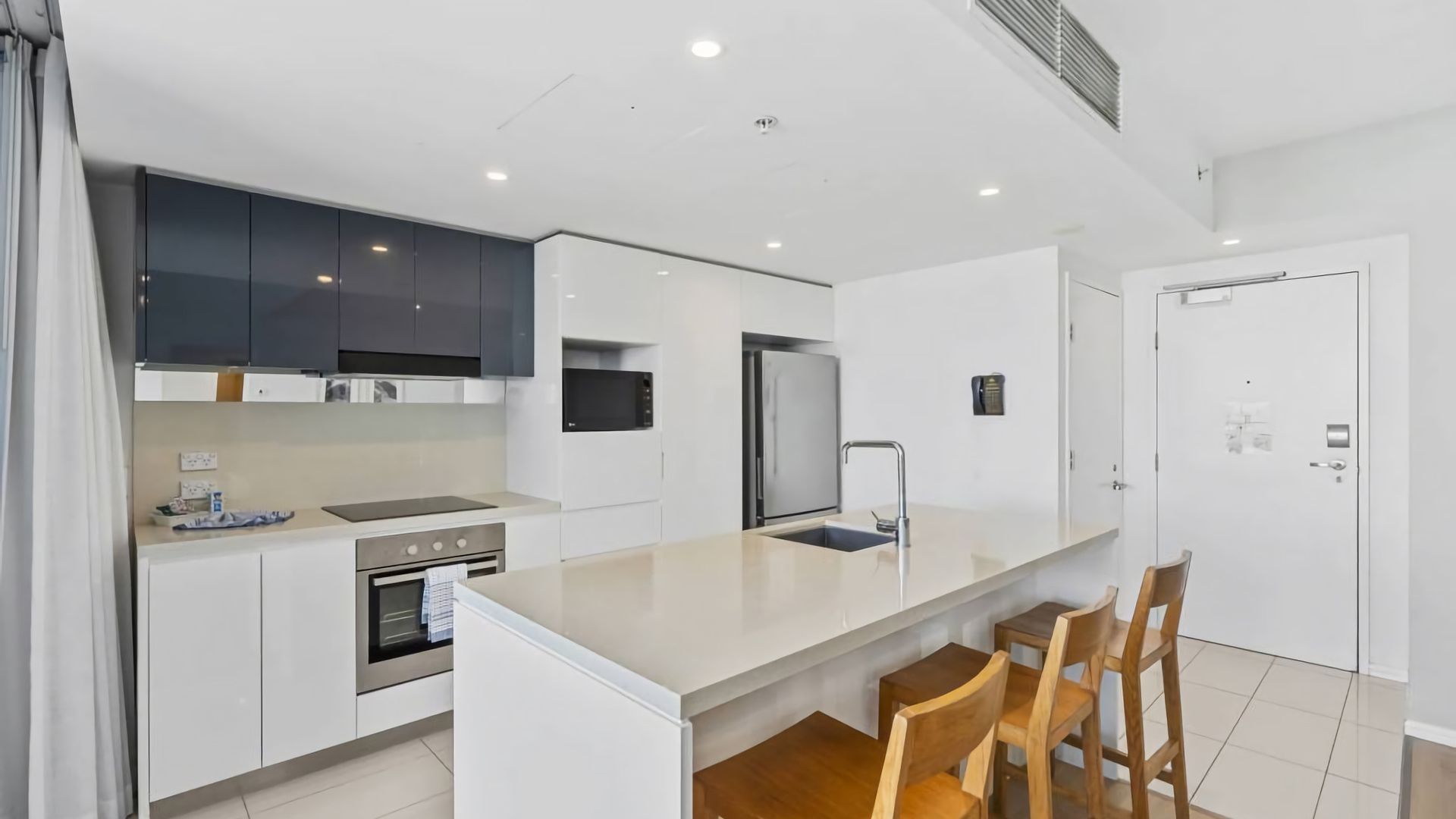 A modern kitchen with a central island, built-in appliances, and a seating area with chairs.