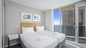 A hotel room with two beds, a large window with a view of buildings, and framed pictures on the wall. - Orchid Residences Apartment 23003 (Surfers Paradise)