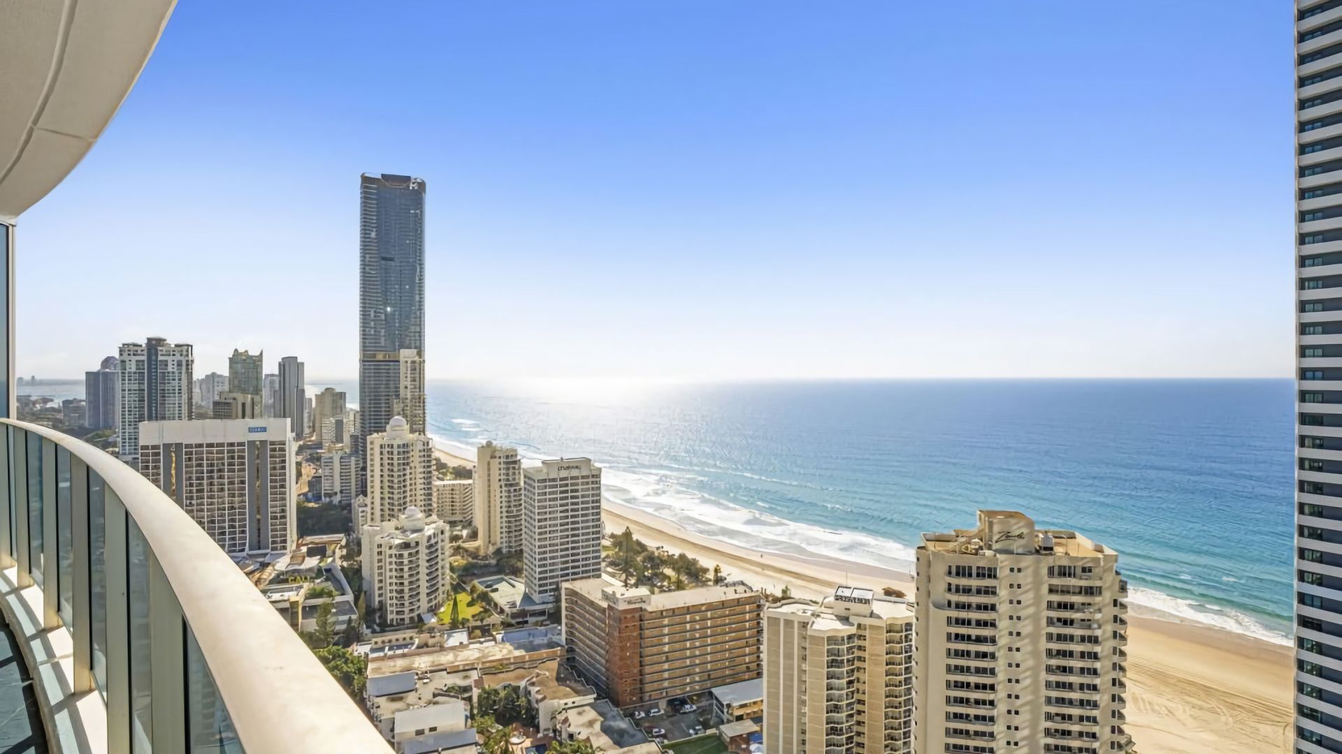 A high-rise building overlooking a beach with a clear view of the ocean and other buildings.
