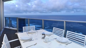 A dining table set for four with a view of the ocean and cityscape. - Orchid Residences Apartment 23403 (Surfers Paradise)