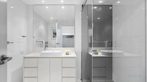 Un bagno moderno con due lavabi, uno spazio doccia in vetro e un grande specchio.