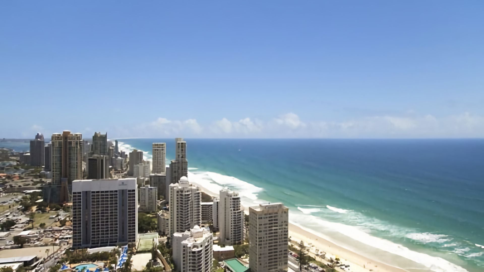 A coastal cityscape with high-rise buildings and a beach.