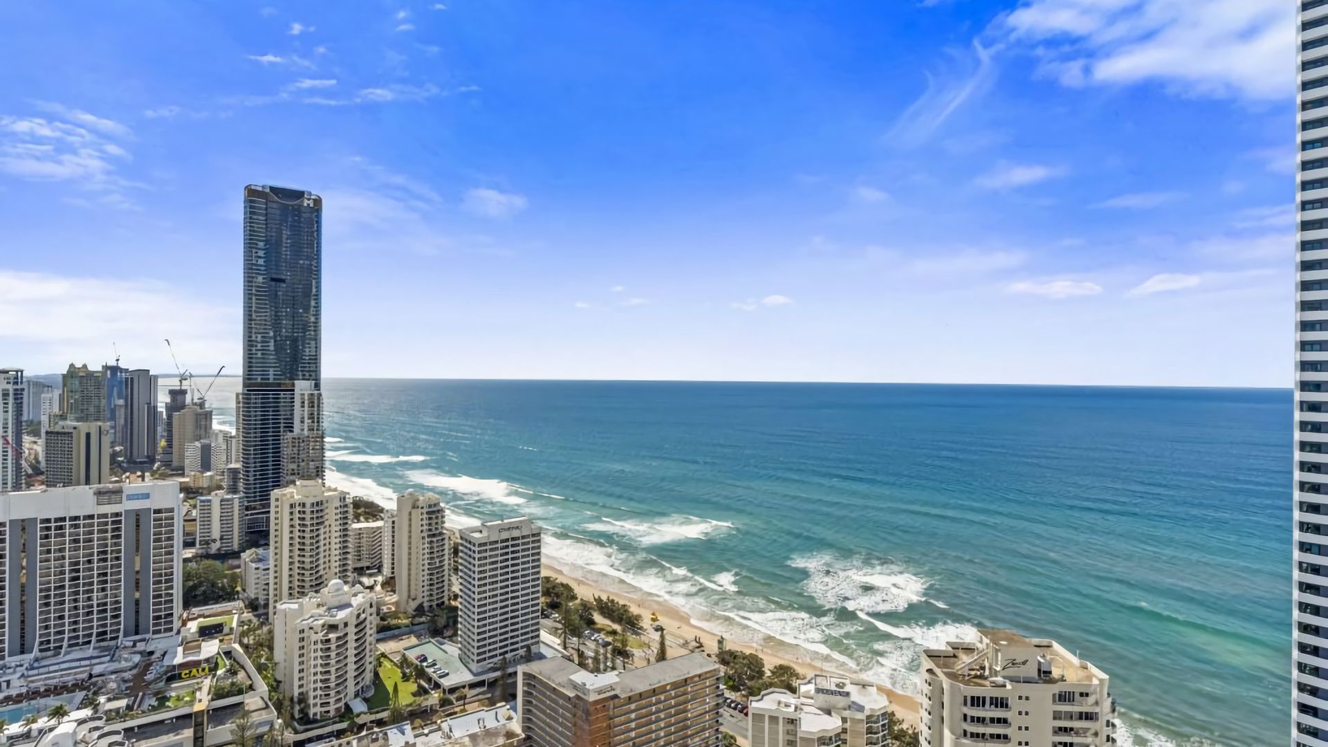 A coastal cityscape with high-rise buildings, a beach, and the ocean.