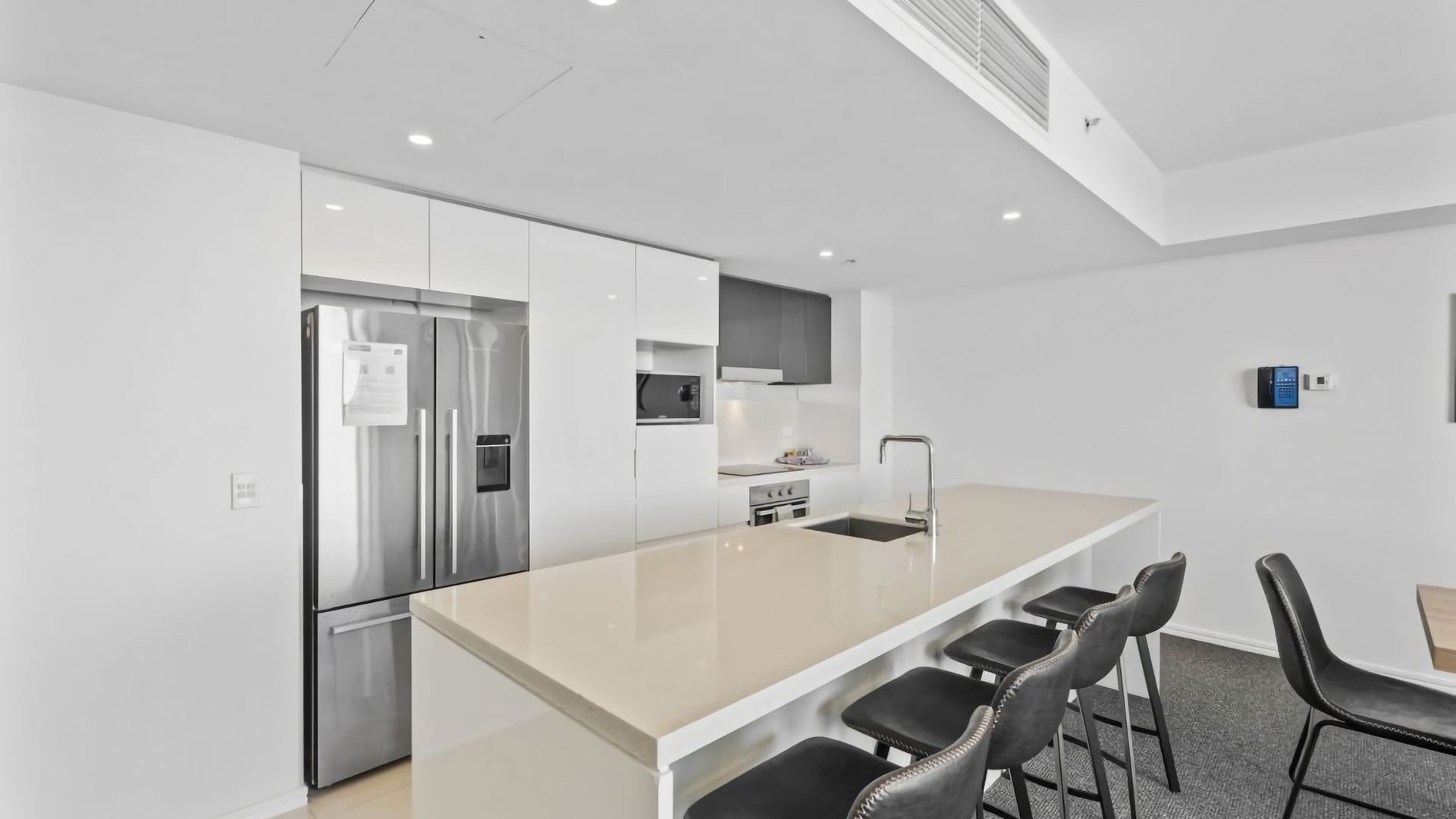 A modern kitchen with a central island, stainless steel appliances, and a built-in microwave.