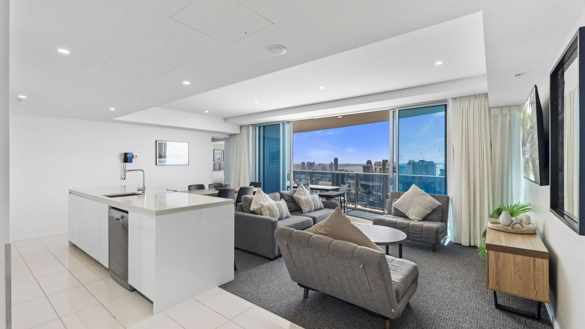 A modern apartment with a kitchen, living area, and large windows offering a city view.