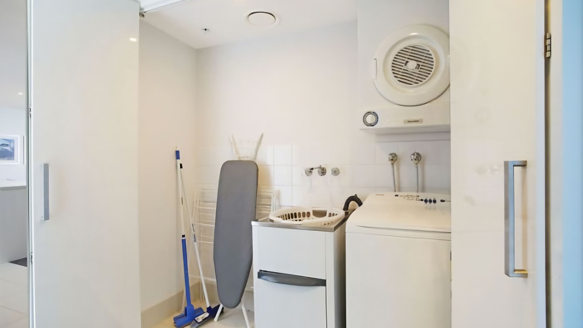 A compact, modern bathroom with a shower, a drying rack, and a washing machine.