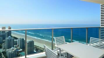 A balcony with a glass railing overlooking a beach and ocean.