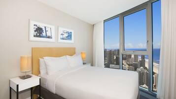 A hotel room with a large bed, two bedside lamps, a nightstand, and two framed pictures on the wall.